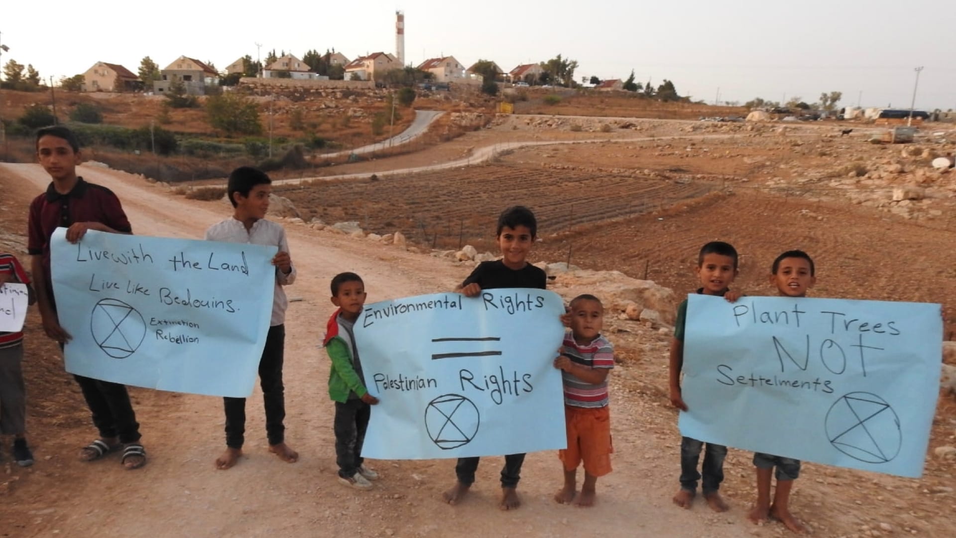 Palestinian children in the Occupied Territories holding hand-made XR signs in 2019